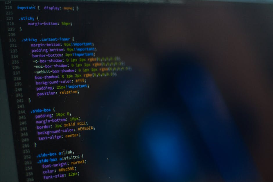 A close-up photograph of a computer screen displaying lines of colorful HTML and CSS programming code. The code includes various style declarations such as margin, padding, border, box-shadow, backgro